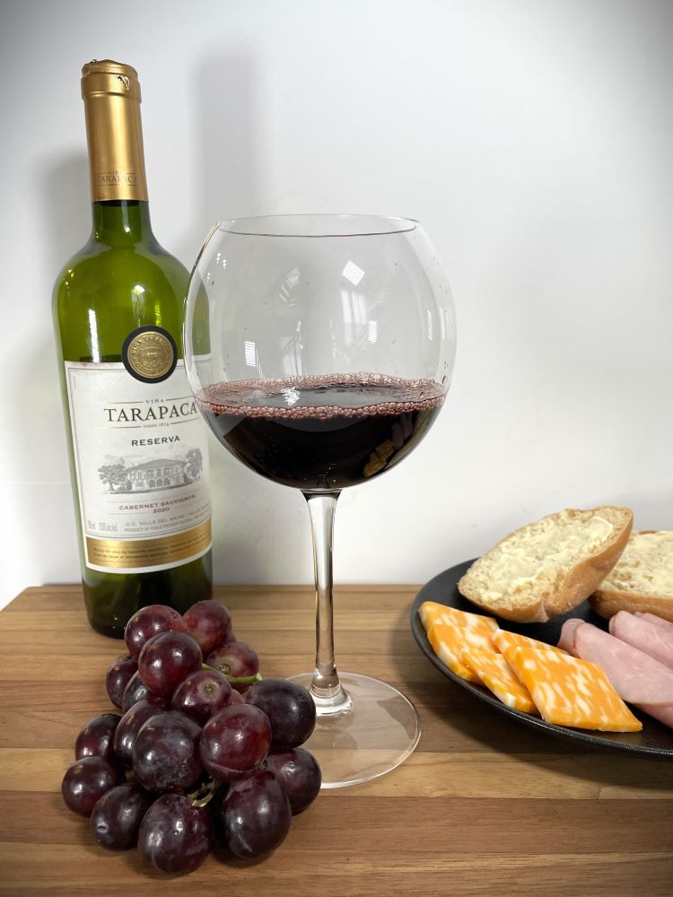 glass of red wine with wine bottle, red grape, bread and cheese