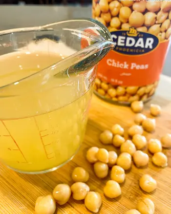 aquafaba in a measuring cup next to a can of chickpeas