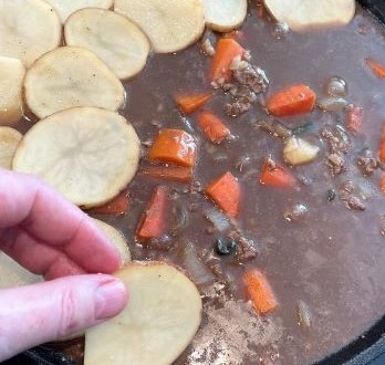 arranging potatoes on beef hotpot