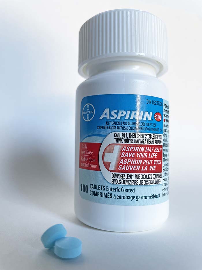 bottle of low dose aspirin with two blue tablets at the base.
