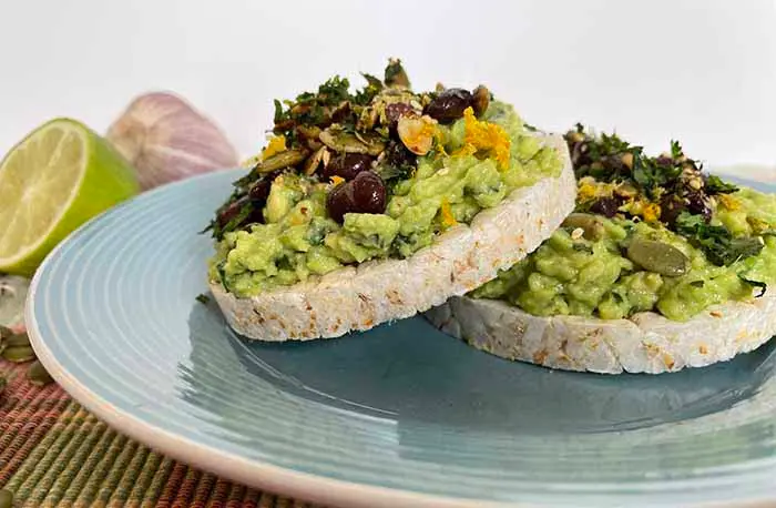 Avocado Rice Cakes on a blue plate with lime on the side Avocado Rice Cakes on a blue plate with lime on the side