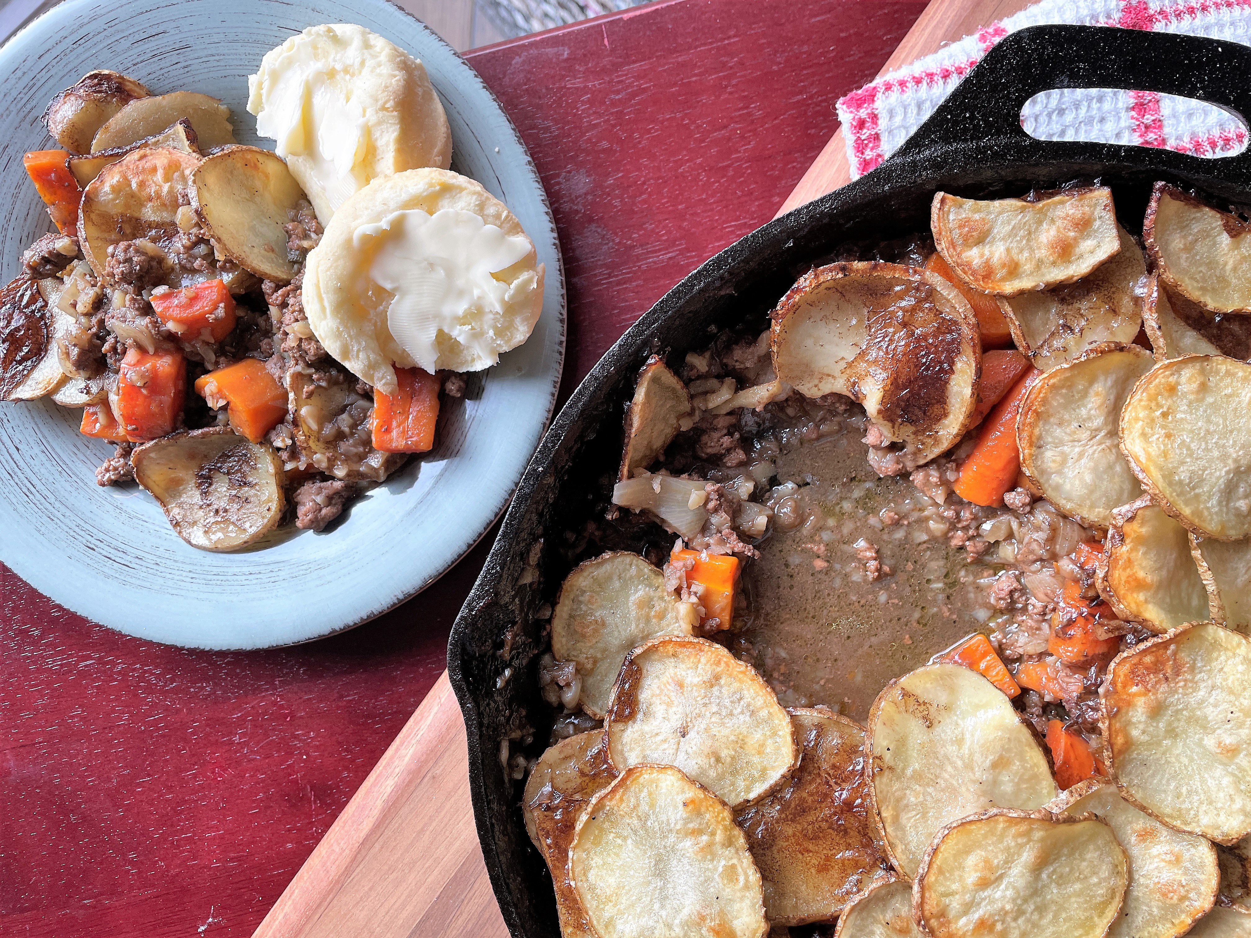 close up of beef hotpot in cast iron pan beside plated hotpot