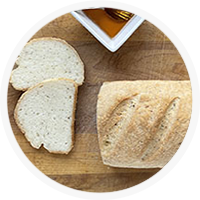 loaf of white bread with a few slices and a bowl of honey