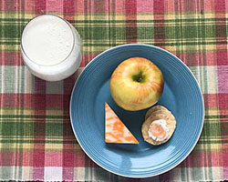 plate with cheese, apple, cracker and goat cheese.  Glass of milk on the side.