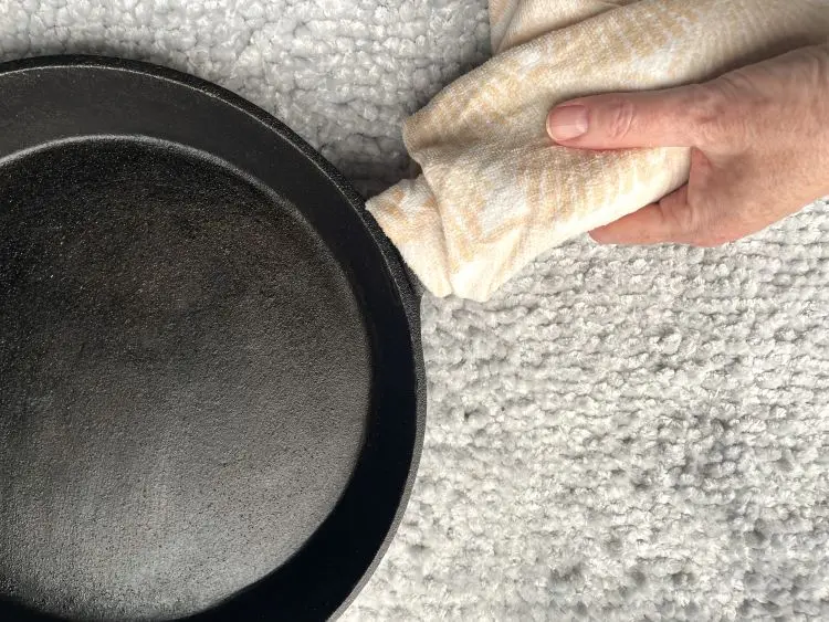 cast iron skillet with towel wrapped around handle