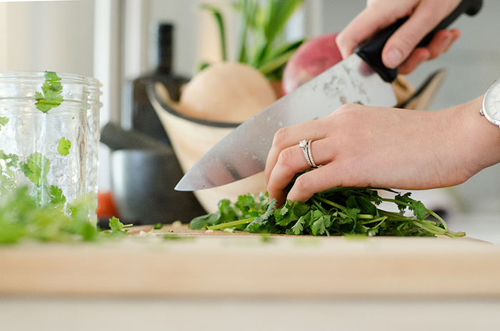 hand with chef's knife chopping herbs.