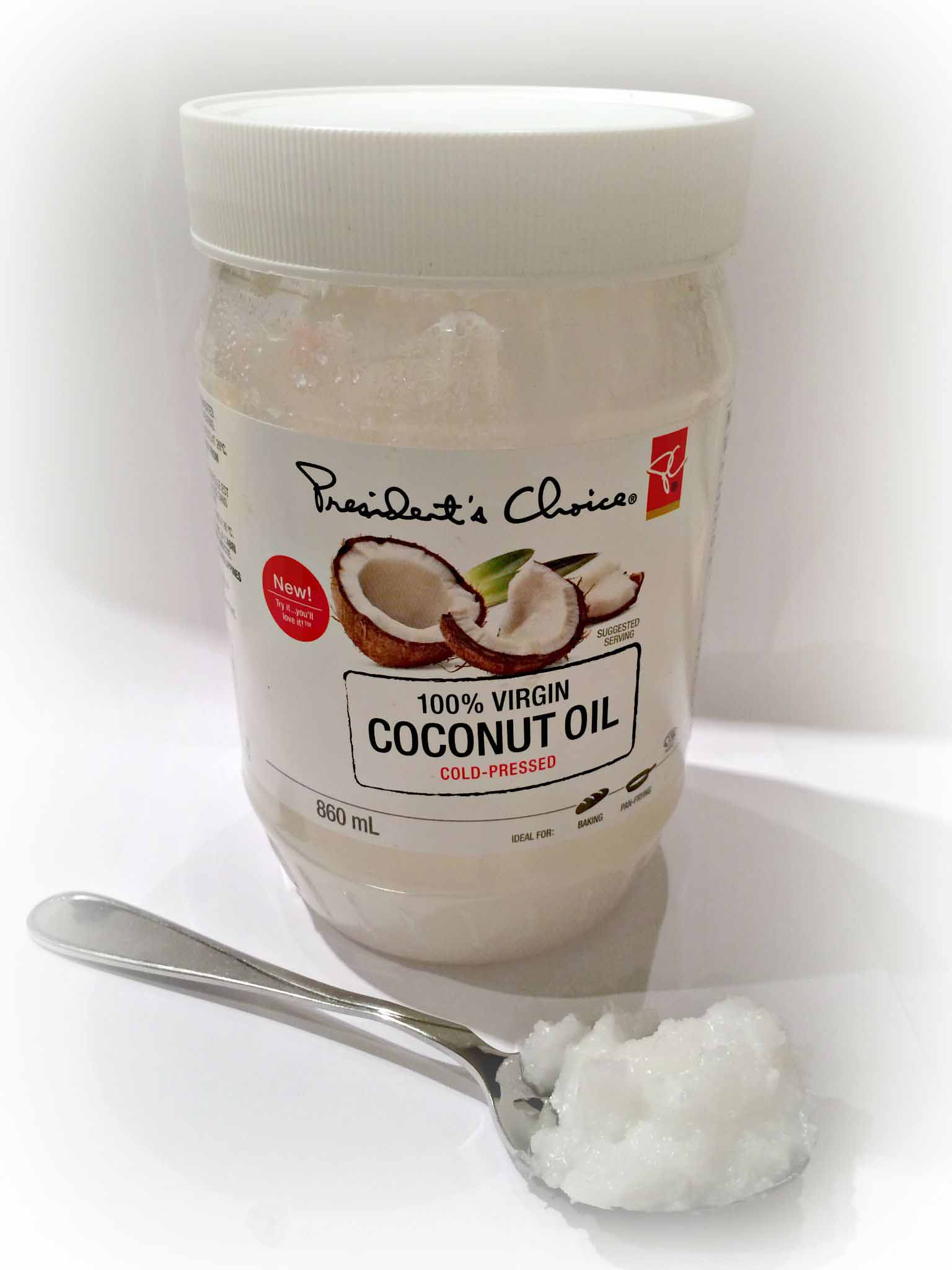 jar of president's choice coconut oil with coconut oil on a spoon.