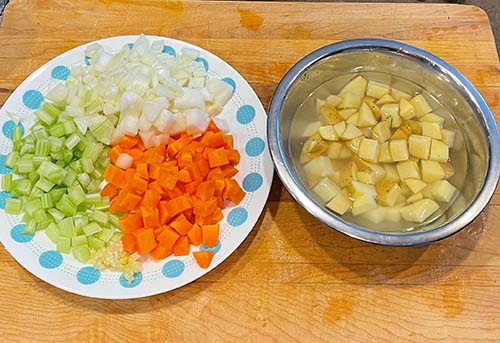 diced vegetables and potatoes on wooded cutting board. diced vegetables and potatoes on wooded cutting board.