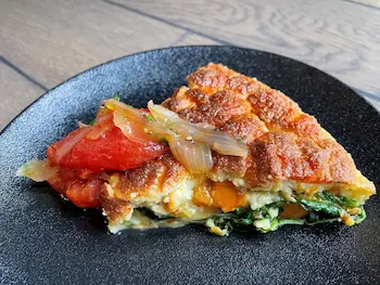 egg frittata with tomato confit on a black plate 
