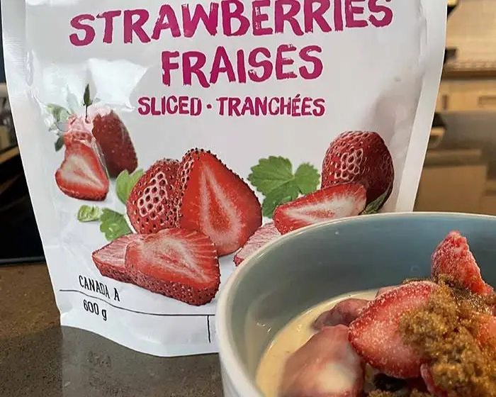 frozen strawberries displayed with a bowl of oatmeal