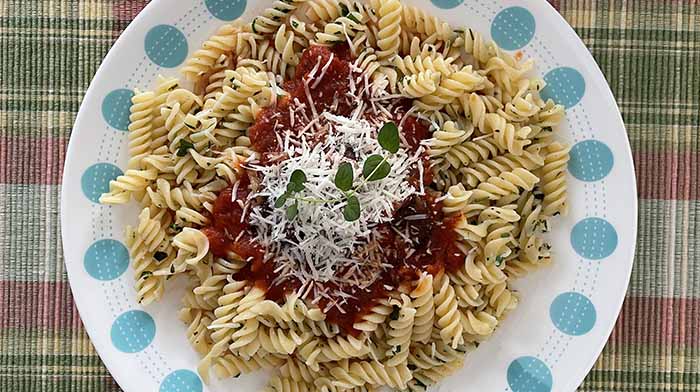 Overhead view of gluten=free fusilli with tomato sauce and shredded cheese. Overhead view of gluten=free fusilli with tomato sauce and shredded cheese.