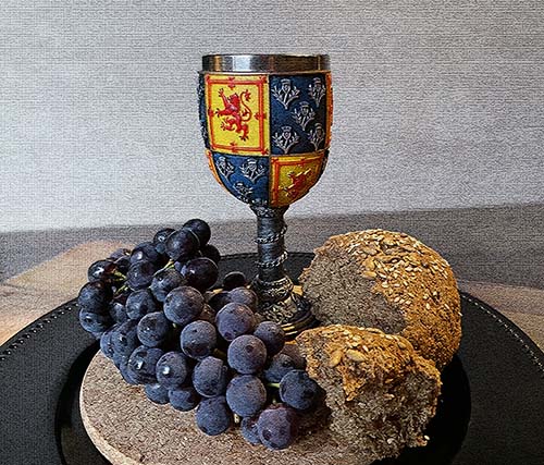Gluten Free Bread: decorative wine chalice with blue grapes and a broken loaf of bread at the base. Gluten Free Bread: decorative wine chalice with blue grapes and a broken loaf of bread at the base.