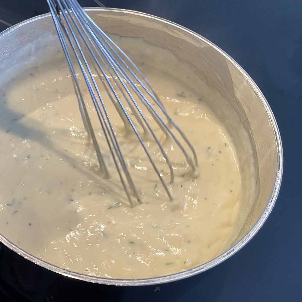white sauce in pot with whisk