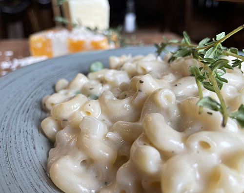 gluten-free mac and cheese on a plate with cheese in background.