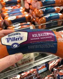 pillar's kolbassa hand held with supermarket shelf in backgournd pillar's kolbassa hand held with supermarket shelf in backgournd