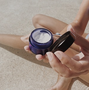 Gluten-free skin care: woman holding and open jars of cream.