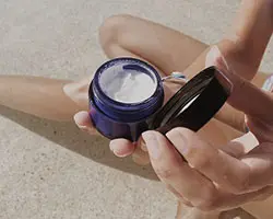 woman opening a container of cream