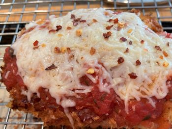 close up of gluten free chicken parm with sauce, cheese and red pepper flakes close up of gluten free chicken parm with sauce, cheese and red pepper flakes