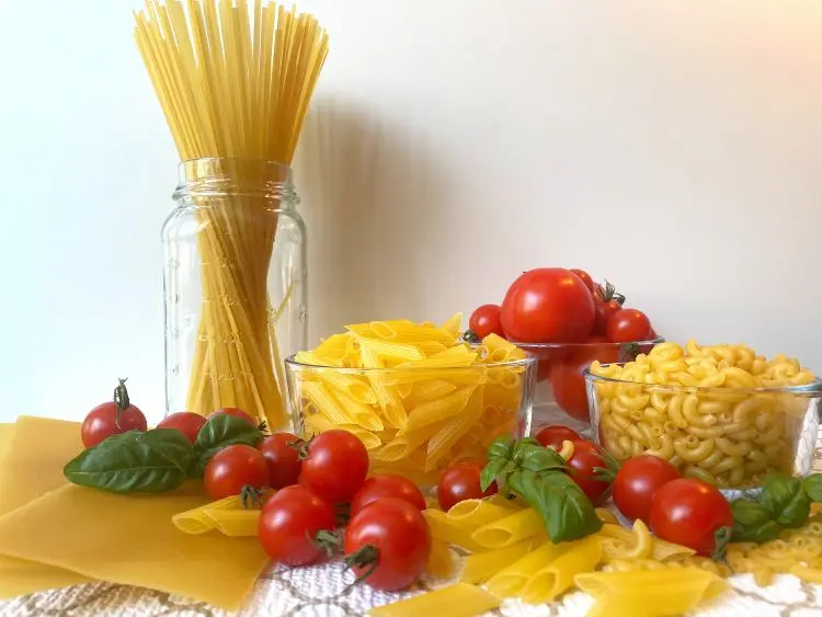 various shapes of gluten free pasta displayed with tomatoes and basil various shapes of gluten free pasta displayed with tomatoes and basil