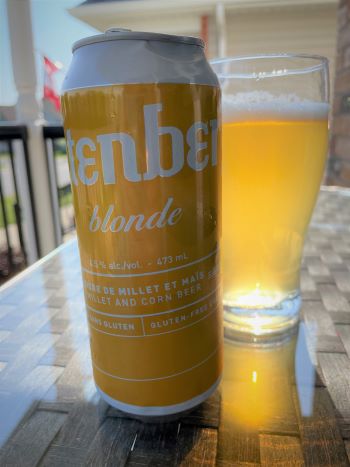 can of Glutenberg blond beer beside a glass of beer on a glass table. can of Glutenberg blond beer beside a glass of beer on a glass table.
