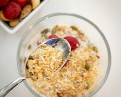 overhead shot of granola cereal in milk beside a bowl of nuts and berries