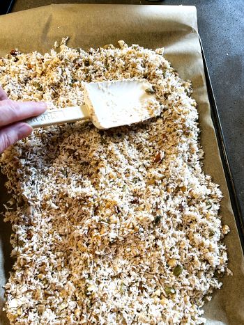 spreading maple nut granola on baking pan