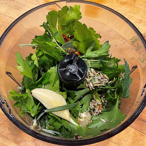 garlic, green herbs and spices in a blender.