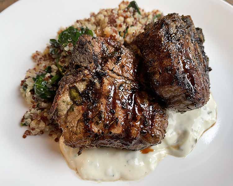 two grilled herbed lamb chops with quinoa plated. two grilled herbed lamb chops with quinoa plated.