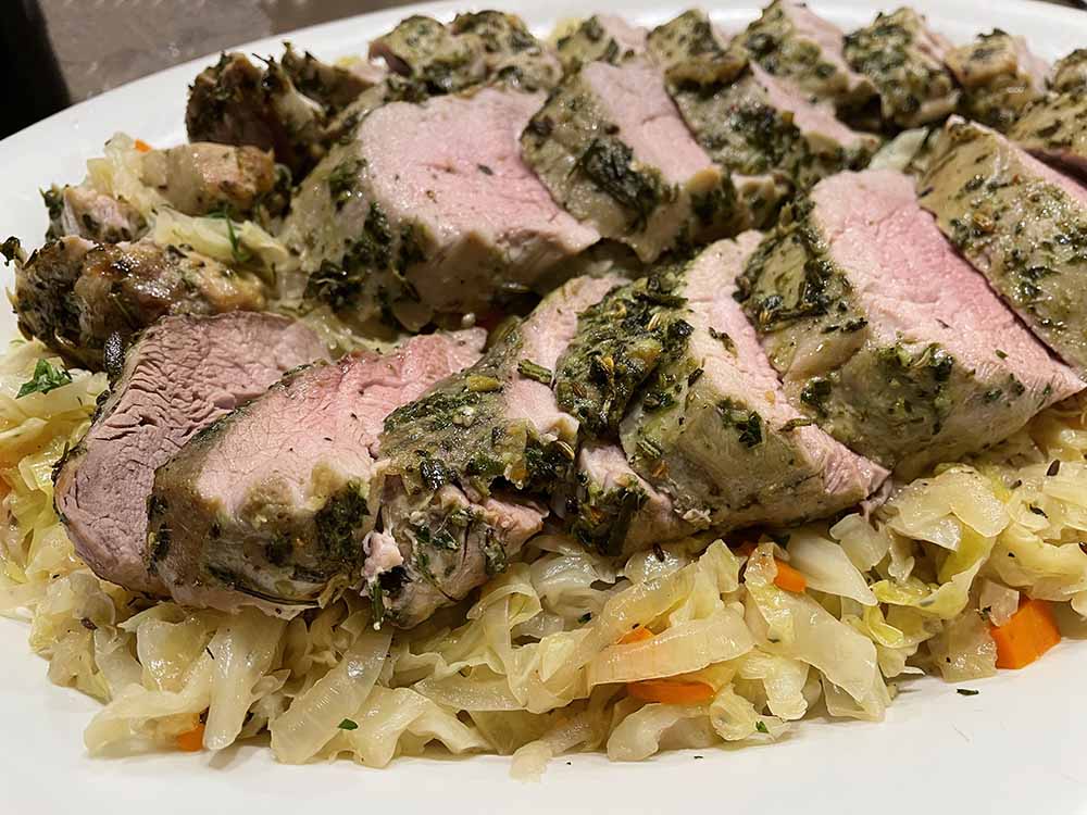 herbed pork tenderloin on a bed of warm cabbage salad