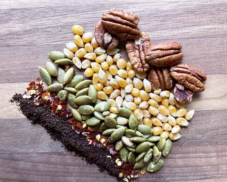 pecans, corn, pumpkin seeds, chilis, coffee on a wooden board.