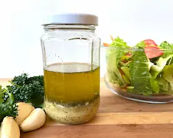 homemade gluten-free salad dressing in a jar with fresh herbs and garlic.