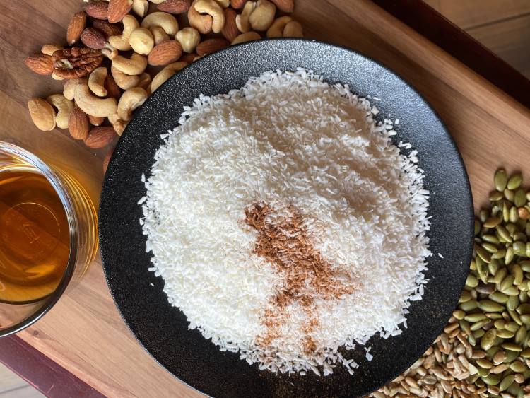 coconut with cinnamon on a black plate with nuts on a wooded board