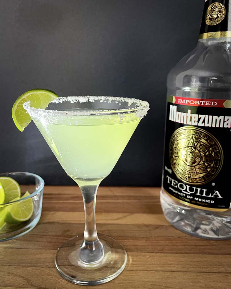 margarita in a martini glass with lime beside tequila bottle margarita in a martini glass with lime beside tequila bottle