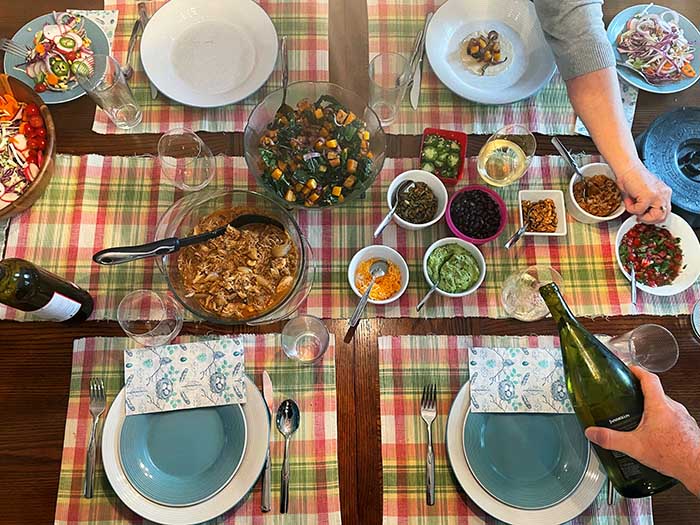 Gluten-Free Meals: Overhead shot of table set with Mexican food. Hands reaching and pouring wine. Gluten-Free Meals: Overhead shot of table set with Mexican food. Hands reaching and pouring wine.