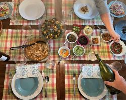 table spread with Mexican dinner.  Hands reaching and pouring wine.