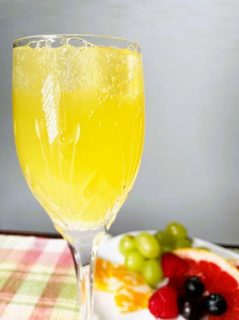 mimosa in champagne glass with fruit in background mimosa in champagne glass with fruit in background