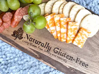 charcuterie board with naturally gluten-free text and logo displaying grapes, cheese, pepperoni and rice crackers