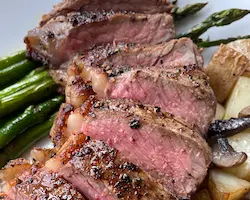pan-fried steak plated with potato and asparagus