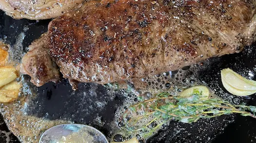 sirloin steak in frying pan with garlic and thyme