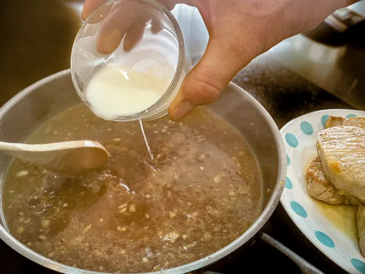 pouring cornstarch slurry into gluten-free gravy pouring cornstarch slurry into gluten-free gravy