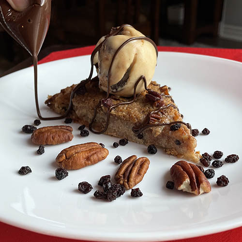 Pear crumble dessert pizza topped with ice cream and chocolate drizzle