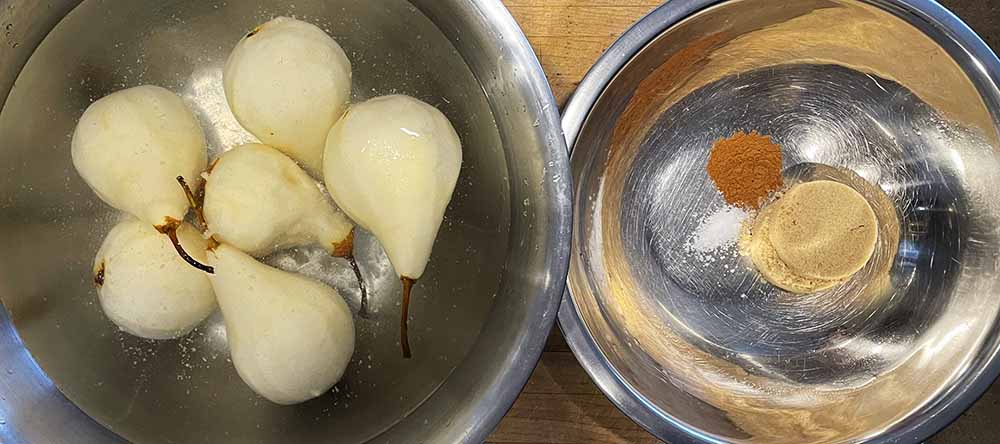 pear crumble pizza filling ingredients.  Bowl of peeled pears on left, bowl with brown sugar, cinnamon and salt on left.