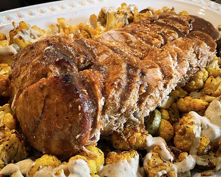 beautiful pork loin roast on a platter with roasted cauliflower. beautiful pork loin roast on a platter with roasted cauliflower.