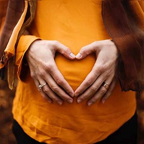 pregnant belly with hands forming a heart.