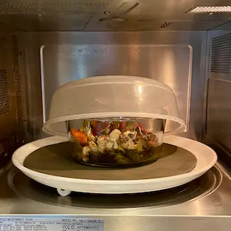 Sheet pan veggies in glass bowl in microwave