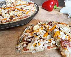 sliced gluten free rice crust pizza topped with cheese and peppers