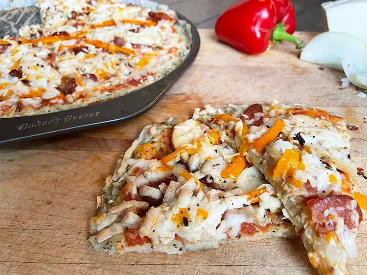 Naturally gluten-free rice crust pizza sliced on a wooden cutting board.