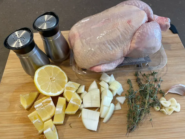 raw whole chicken with salt, pepper, lemon, onion, garlic, thyme