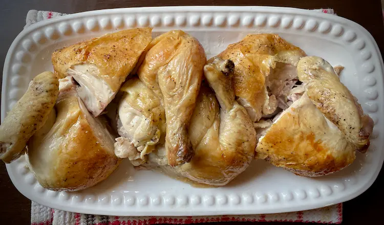 roast chicken, carved and displayed on a white platter