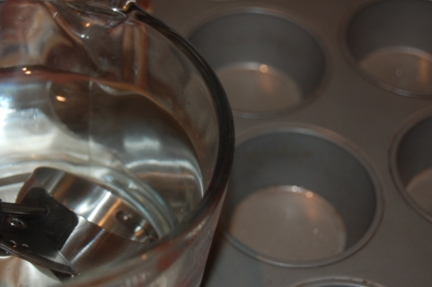 adding water to unfilled muffin tins